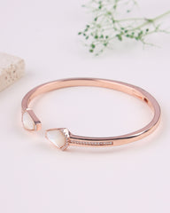 Rose gold bracelet with a white stone on a light background