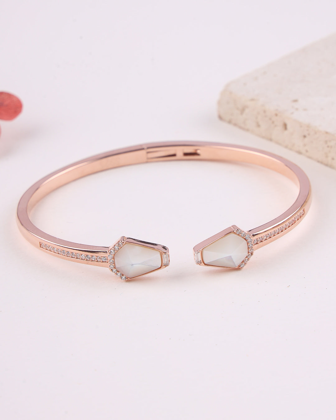 Rose gold bracelet with gemstone ends on a light background