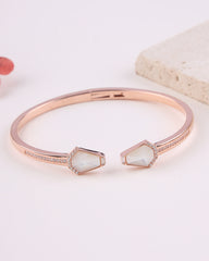 Rose gold bracelet with gemstone ends on a light background