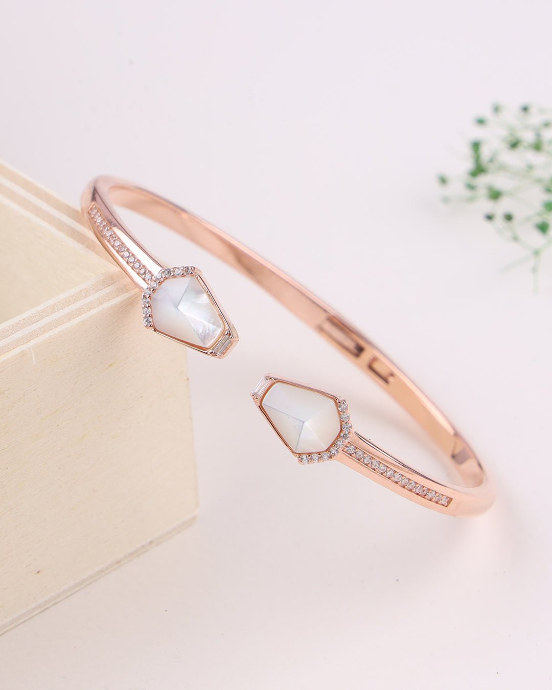 Rose gold bracelet with a central gemstone on a light background
