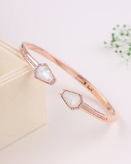 Rose gold bracelet with a central gemstone on a light background