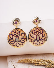 Gold lotus flower earrings with purple accents on a white surface.