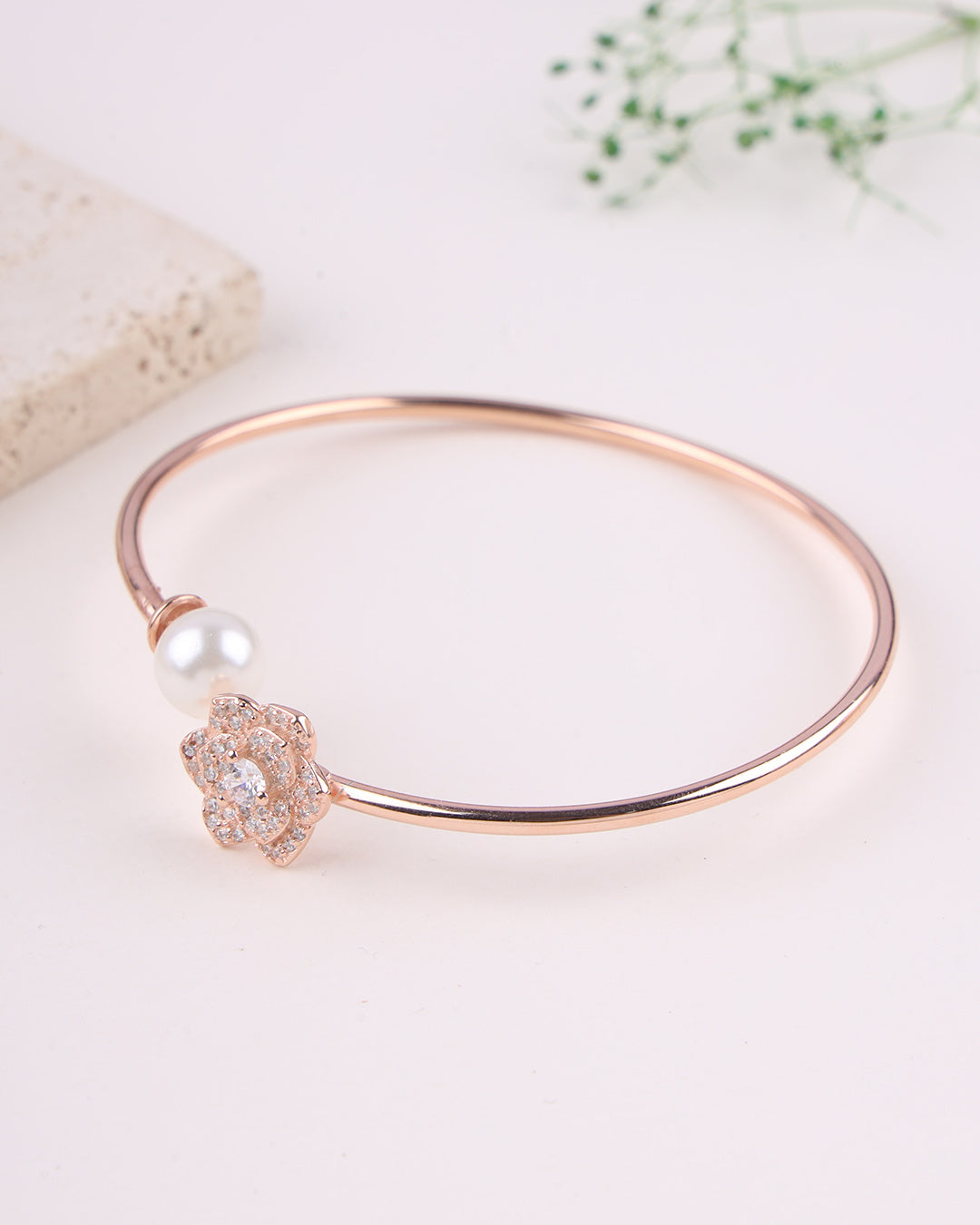 Rose gold bracelet with a pearl and crystal charm on a light background