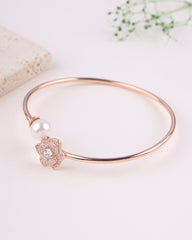 Rose gold bracelet with a pearl and crystal charm on a light background