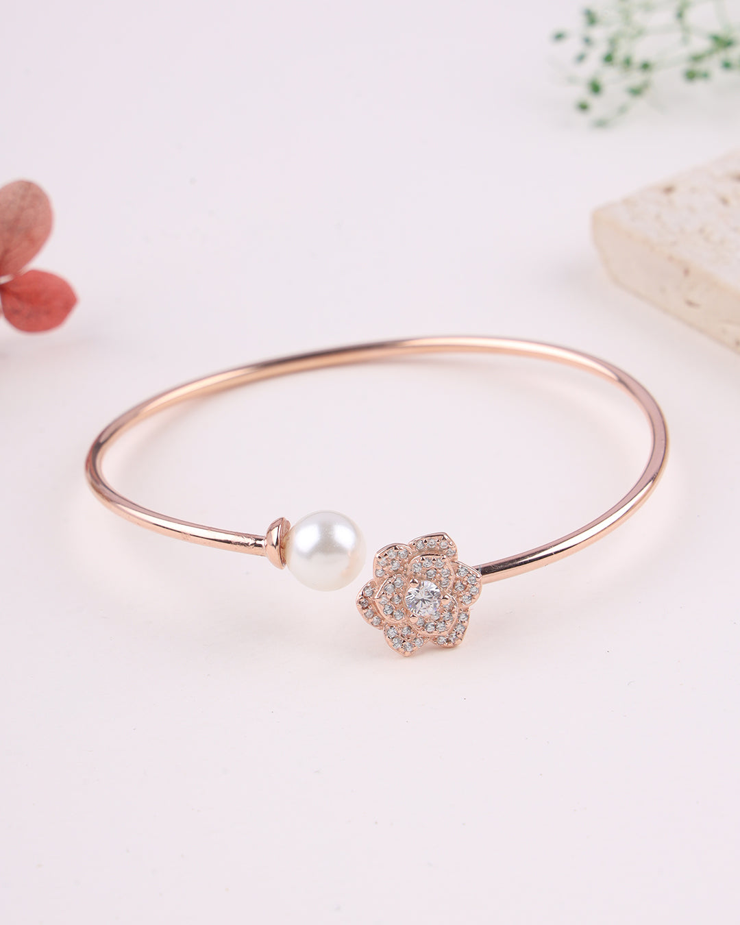 Rose gold bracelet with pearl and crystal charm on a light background