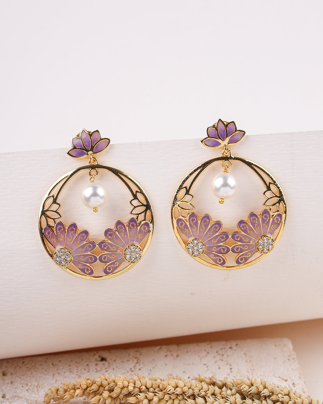 Pair of earrings with floral designs and purple accents on a white surface.