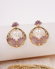 Pair of earrings with floral designs and purple accents on a white surface.