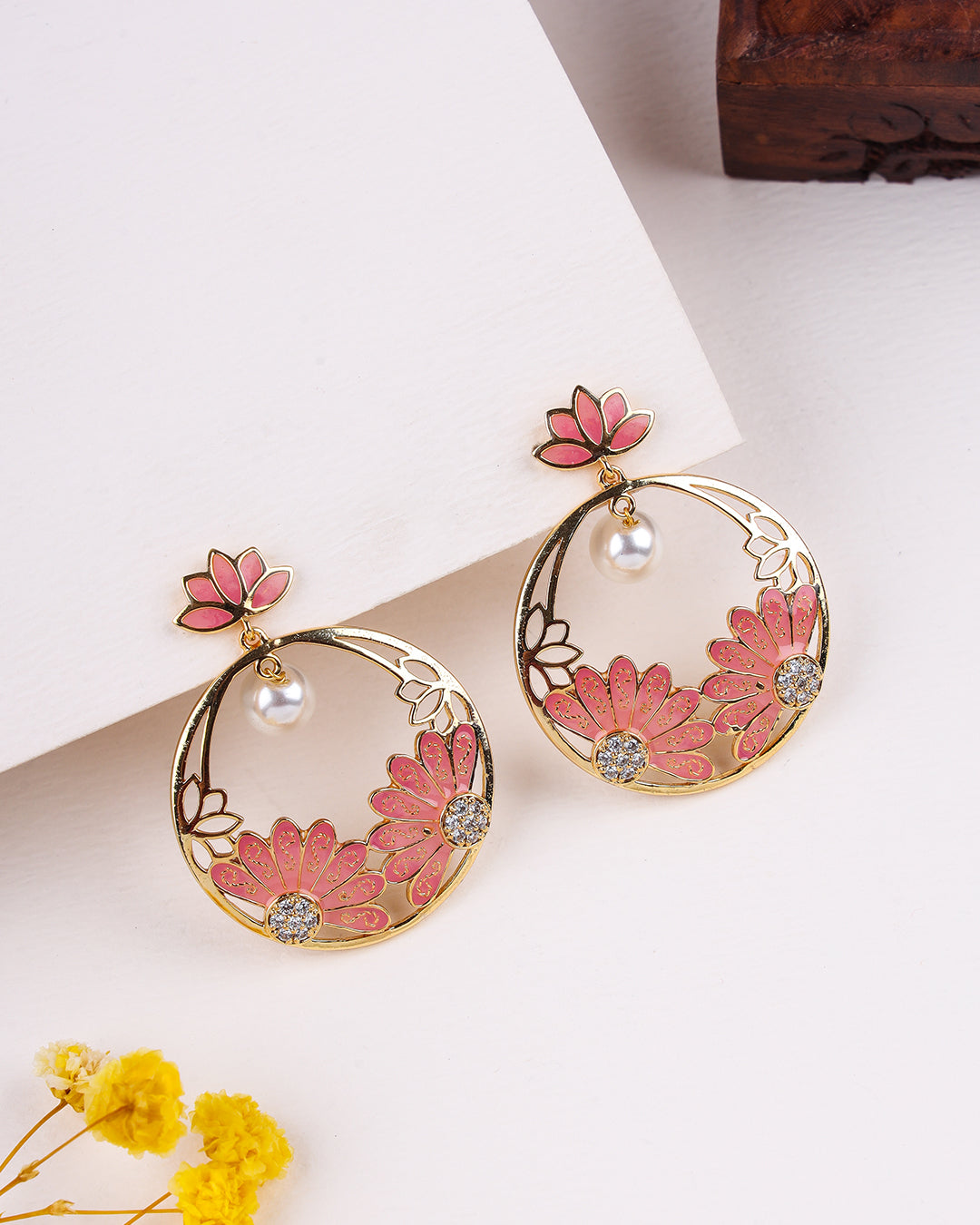 Pair of floral earrings with pink flowers and gold frames on a light background
