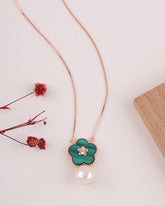 Necklace with green clover pendant and pearl on a light background