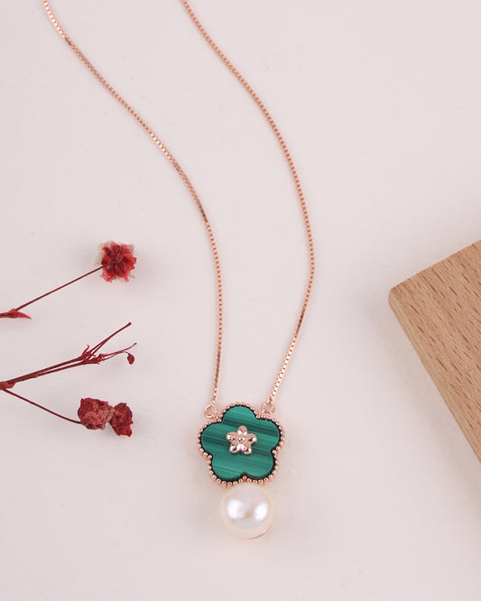 Necklace with green clover pendant and pearl on a light background