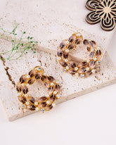 Pair of hoop earrings with brown gemstones on a textured surface