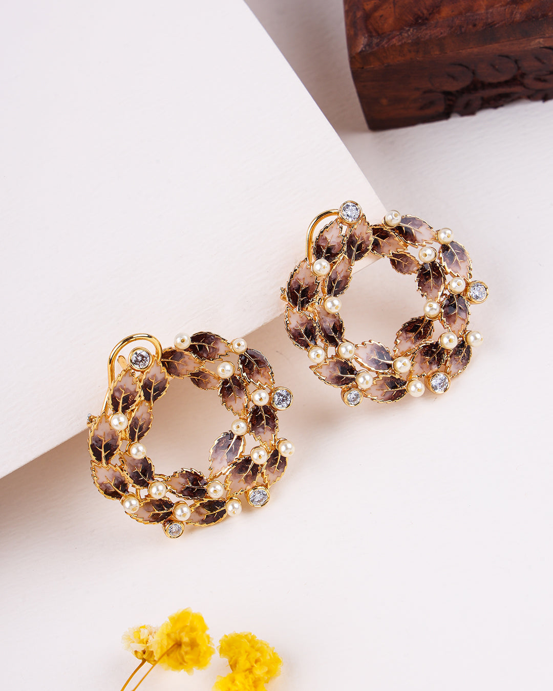Pair of decorative earrings with gold and brown elements on a light background