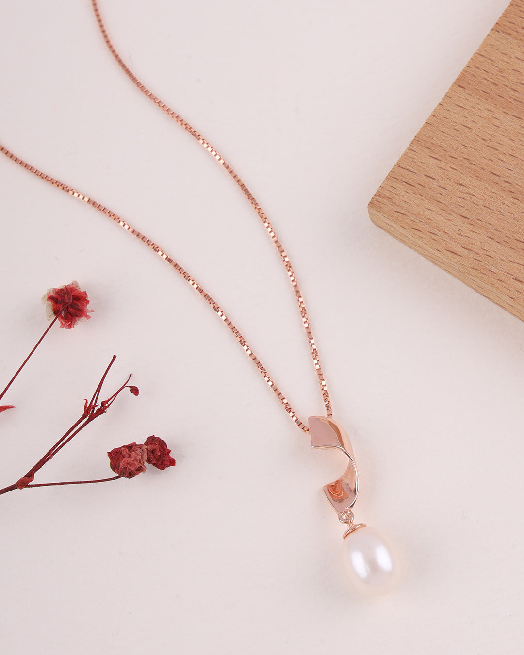 Rose gold necklace with a pearl pendant on a light background