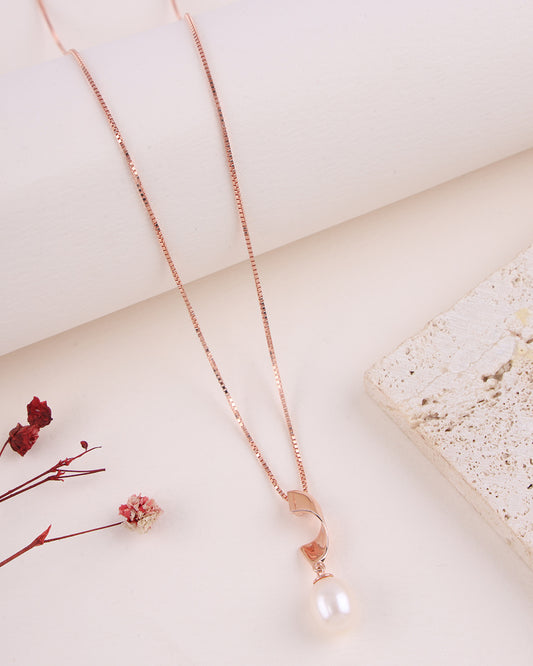 Rose gold necklace with a pearl pendant on a light background