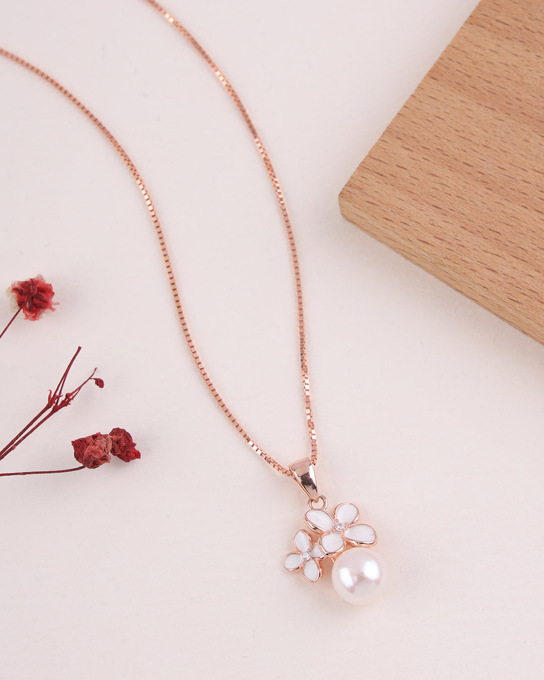 Rose gold necklace with a floral pendant on a light surface
