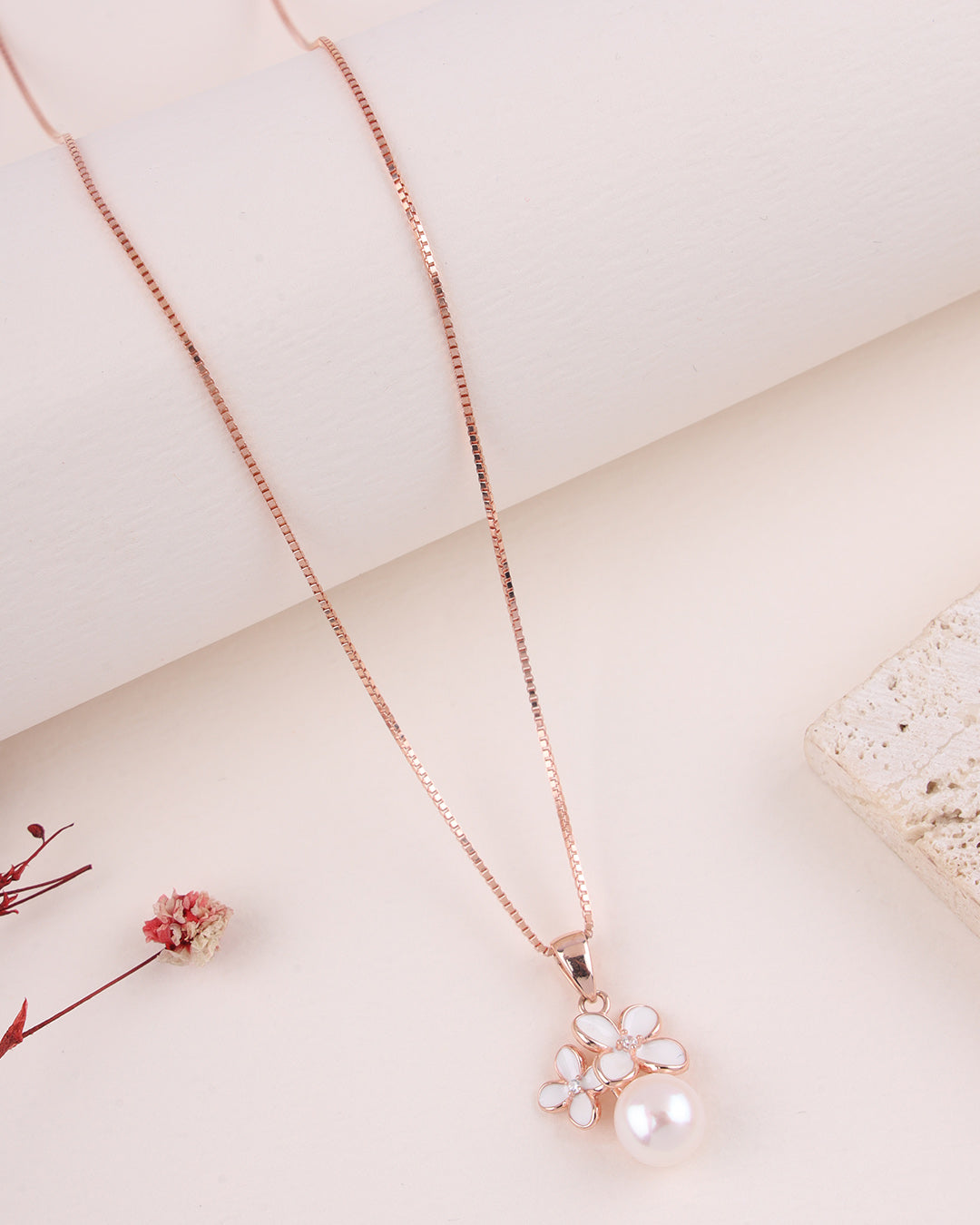 Rose gold necklace with a floral pendant on a light background