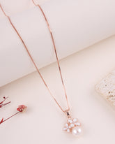 Rose gold necklace with a floral pendant on a light background
