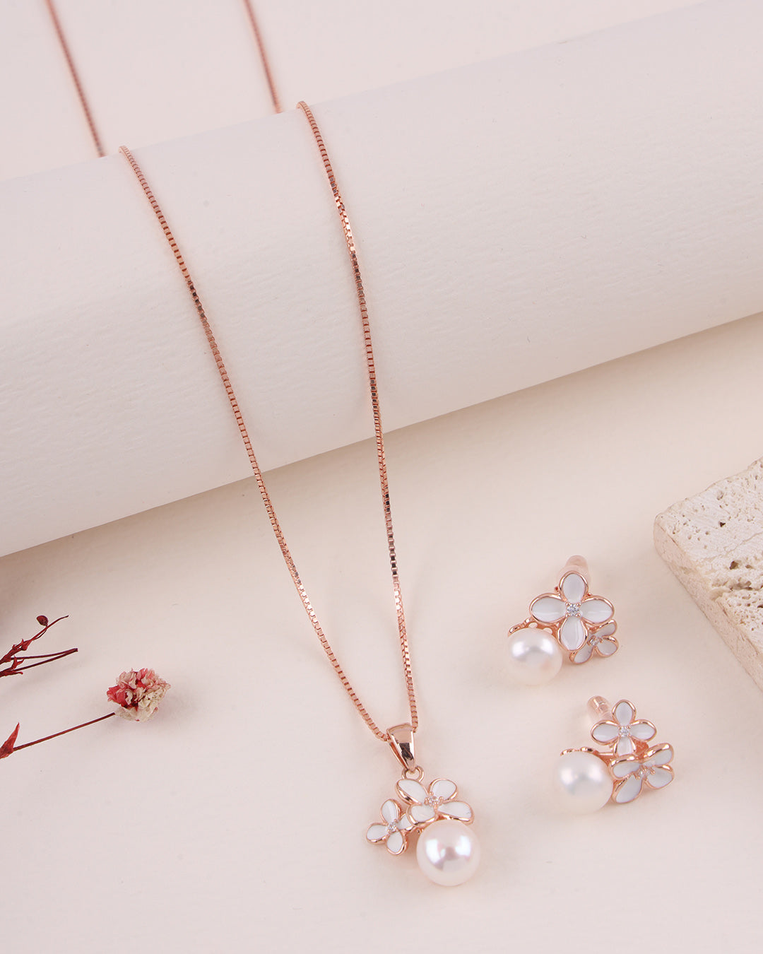 Rose gold jewelry set with floral designs on a light background