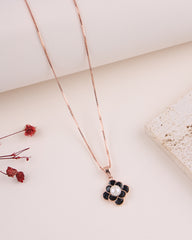 Rose gold necklace with a black floral pendant on a light background