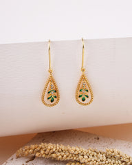 Gold earrings with green gemstones on a white surface
