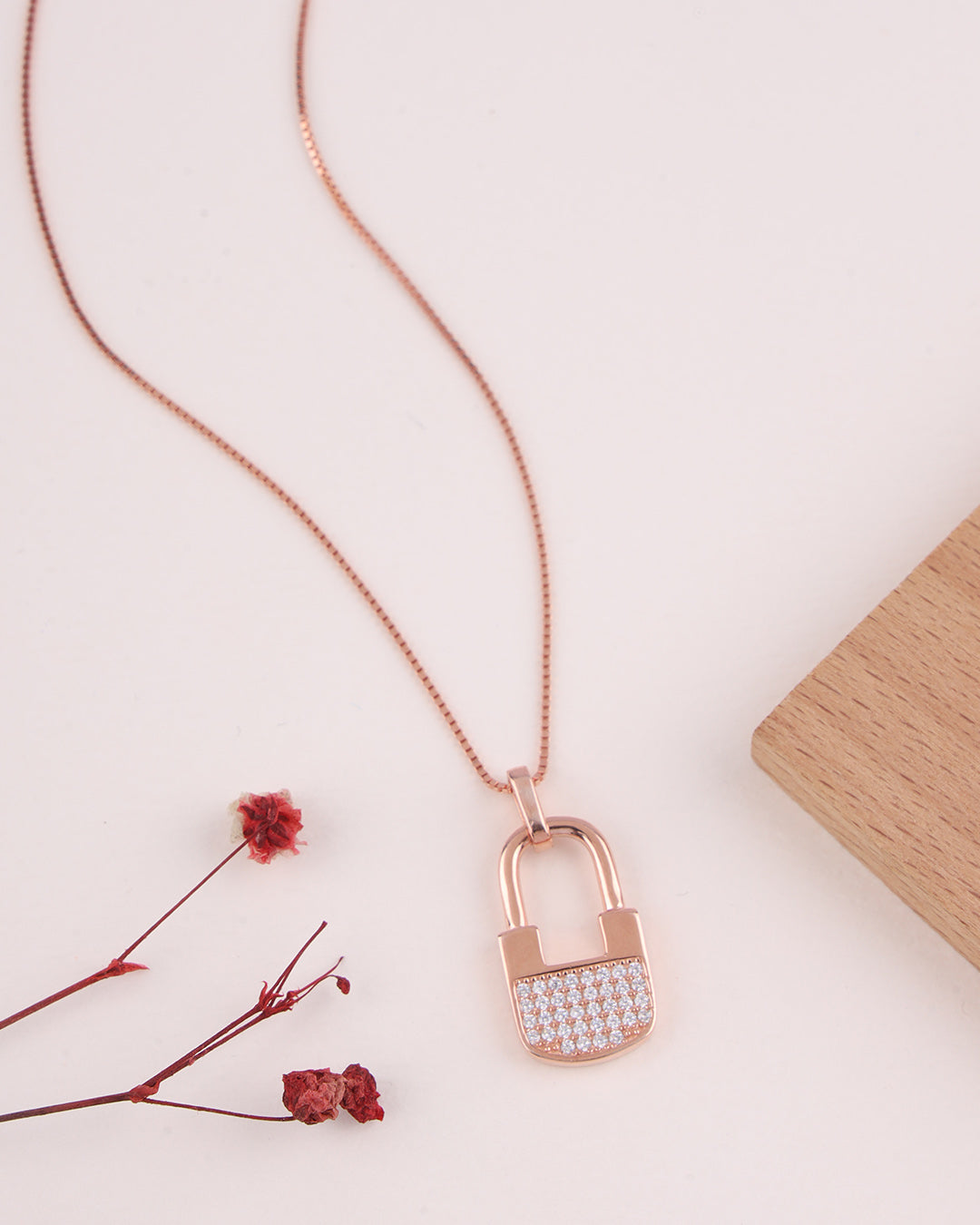 Rose gold necklace with a lock-shaped pendant on a light background