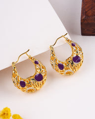 Gold hoop earrings with purple stones on a light background