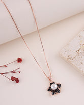 Rose gold necklace with a black and white pendant on a light surface.