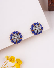 Pair of blue floral earrings with gold accents on a light background