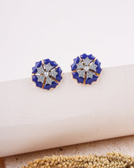 Pair of blue floral earrings with gold accents on a beige surface.