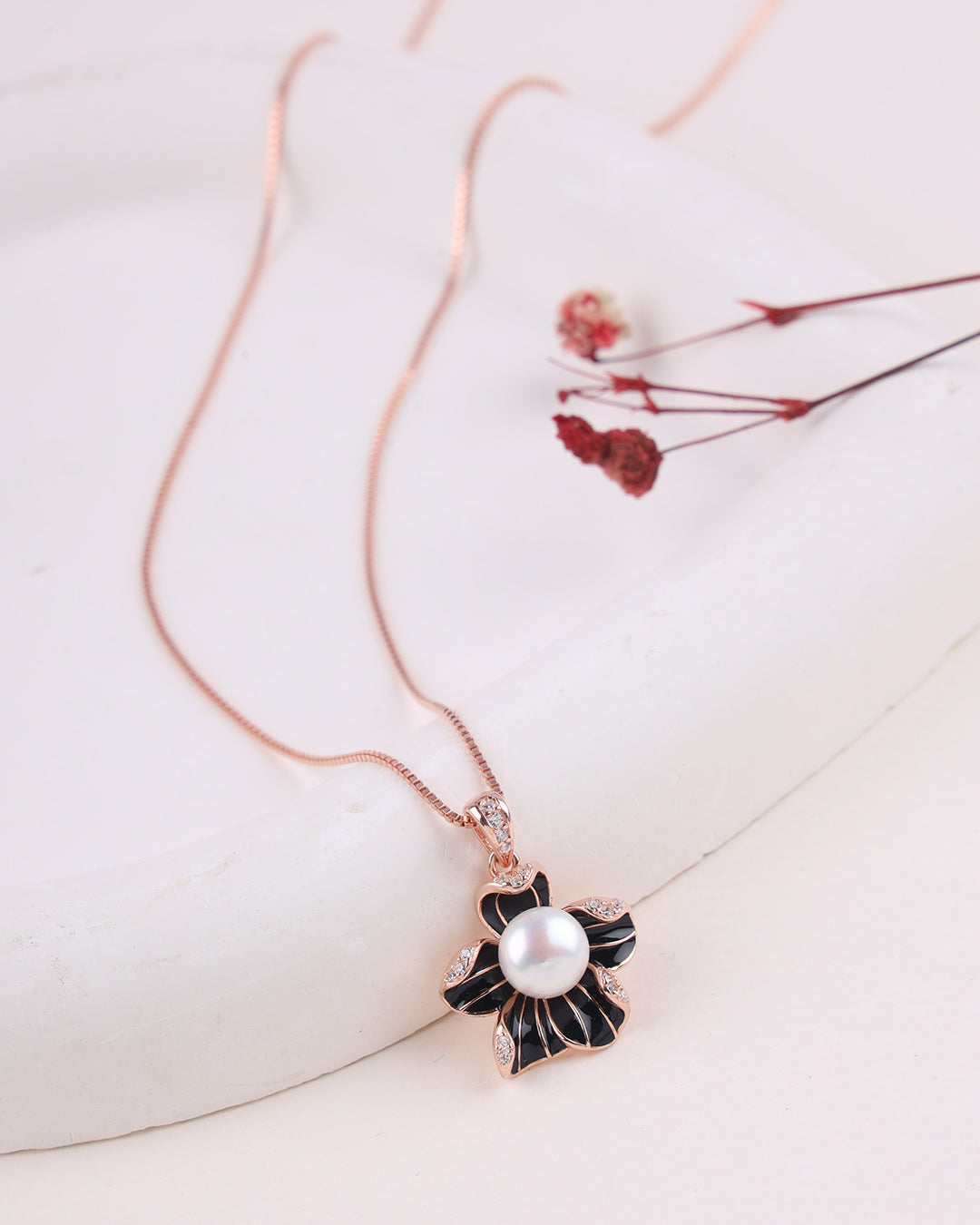 Necklace with a floral pendant featuring a pearl on a light background