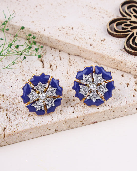 Pair of blue floral earrings with gold accents on a textured surface.