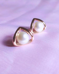 Pearl earrings with rose gold frames on a pink background