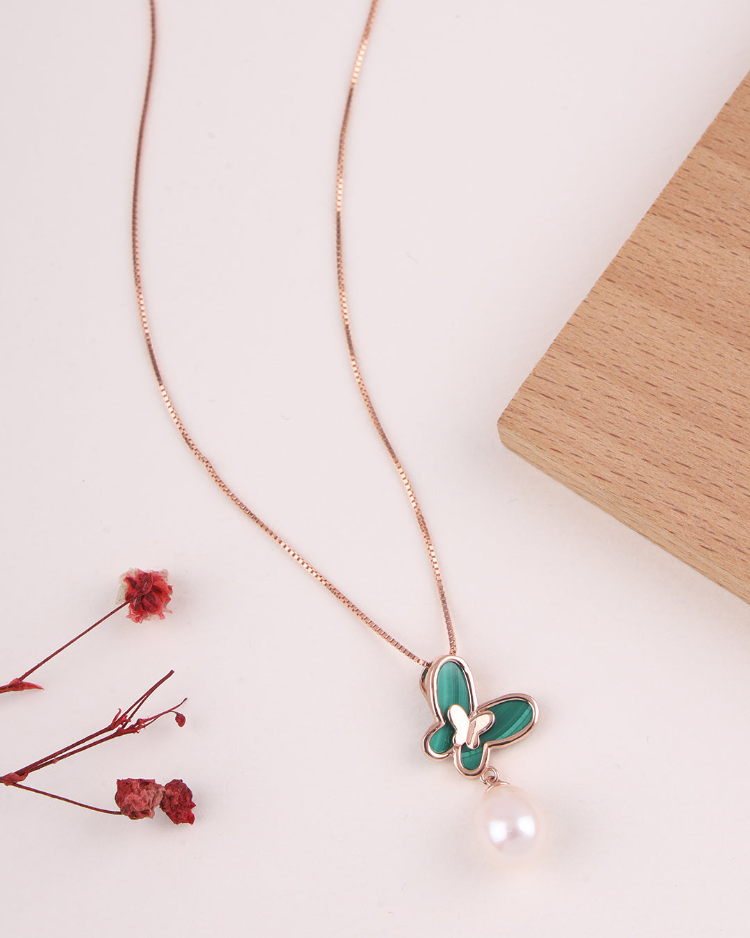 Butterfly necklace with green details on a light background