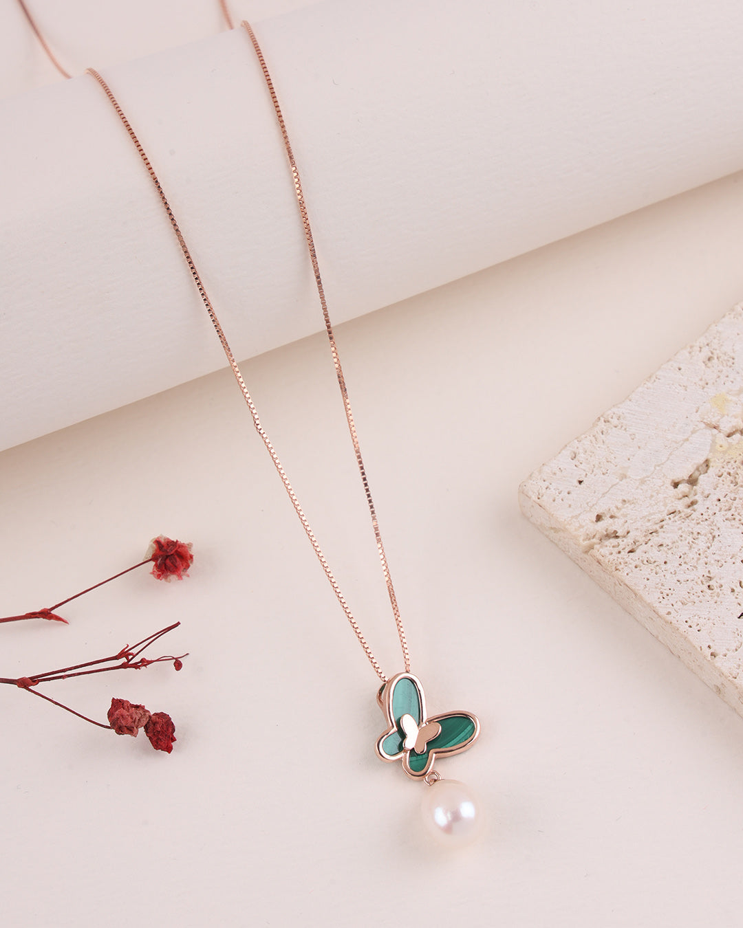 Necklace with a green butterfly pendant and pearl on a light background