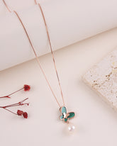 Necklace with a green butterfly pendant and pearl on a light background