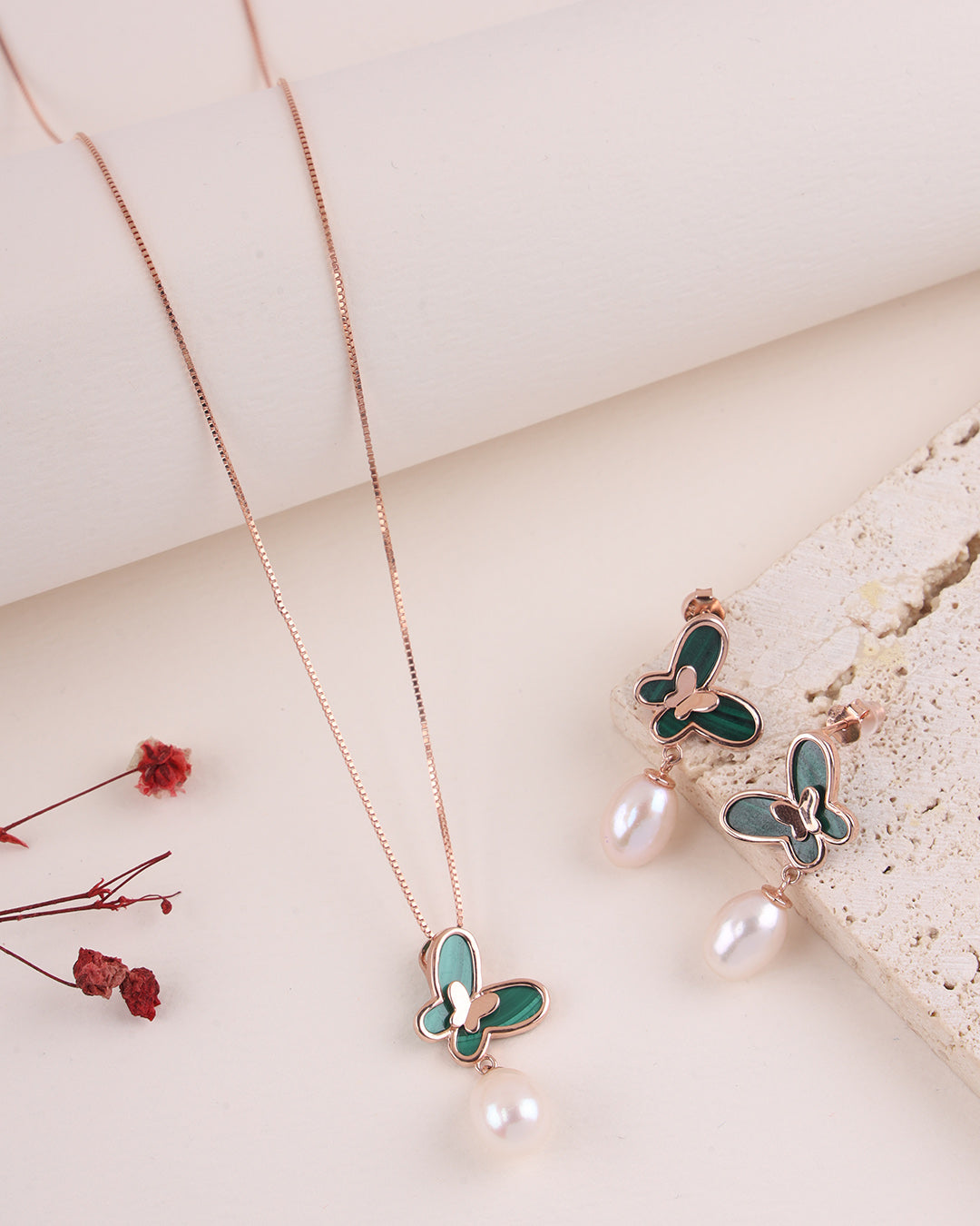 Butterfly necklace and earrings with green butterfly wings and pearl accents on a light background.