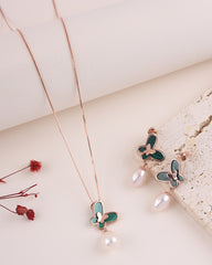 Butterfly necklace and earrings with green butterfly wings and pearl accents on a light background.