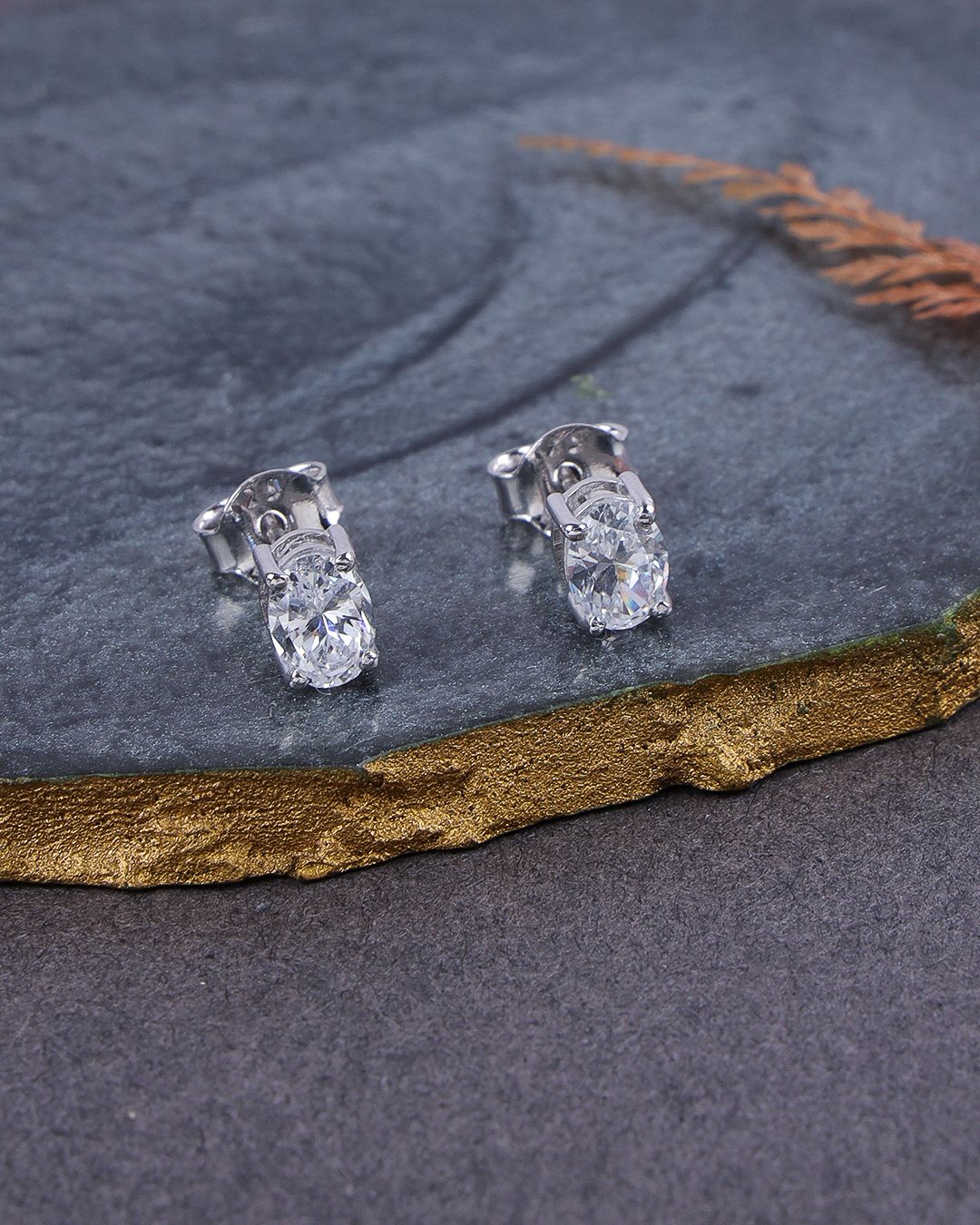 Pair of diamond stud earrings on a dark stone surface