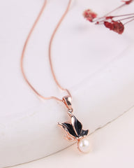 Rose gold necklace with a leaf and pearl pendant on a white background