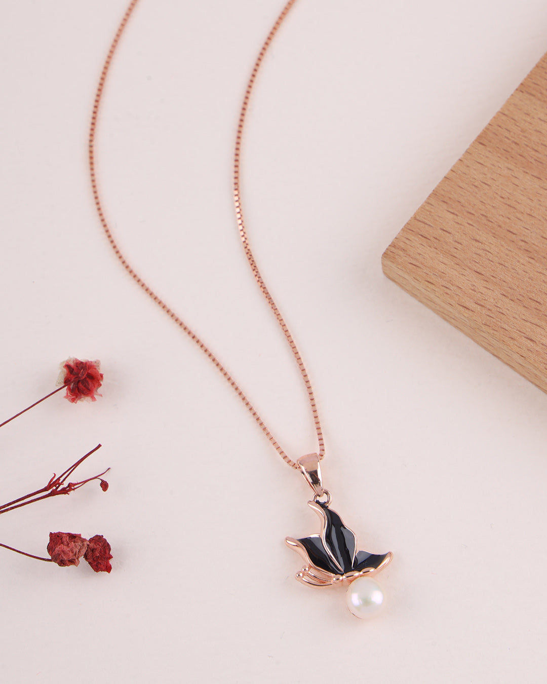 Necklace with a black leaf pendant and pearl on a light background