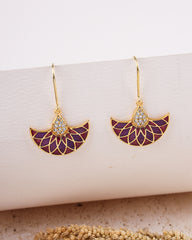 Gold and purple earrings on a white surface