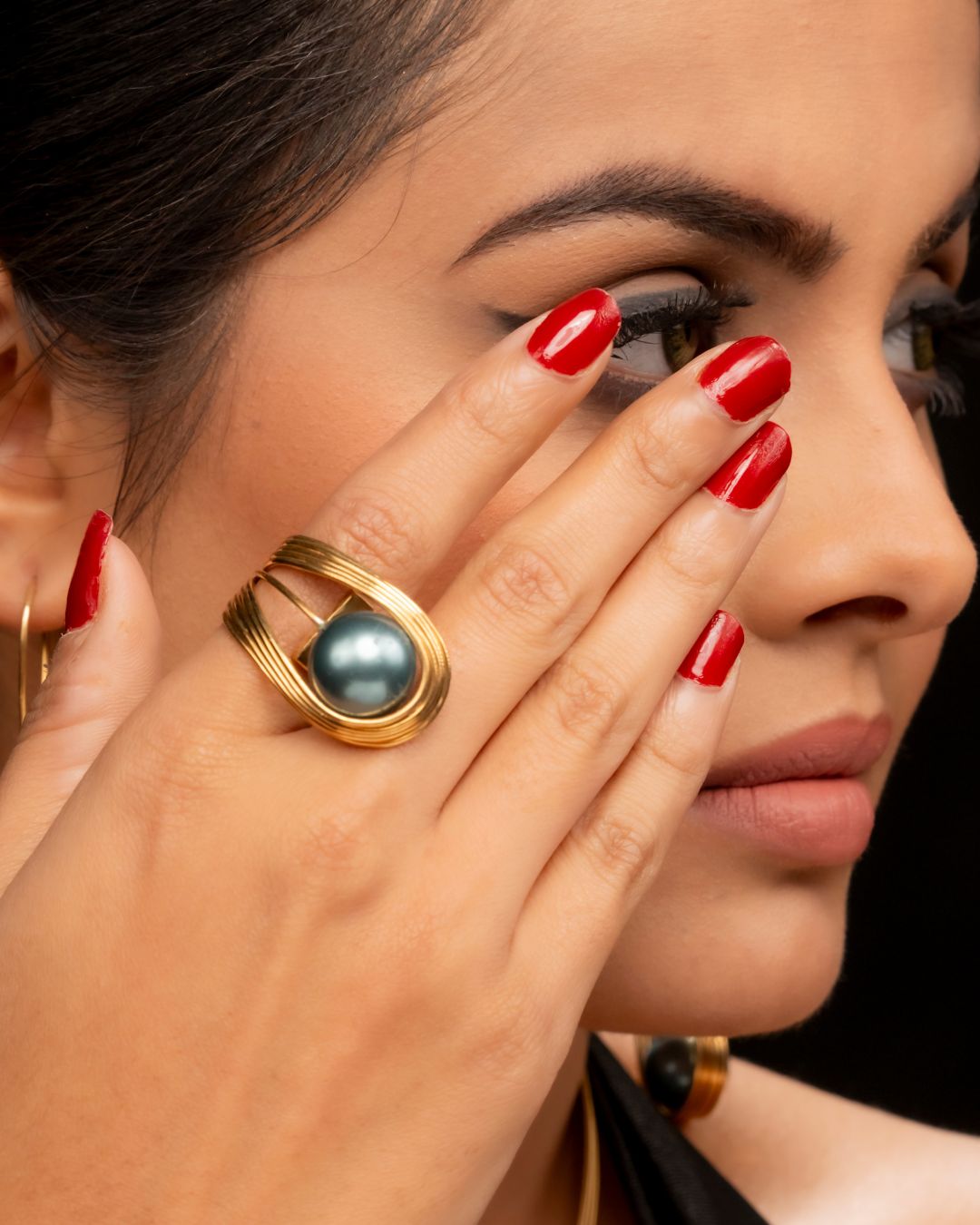 Woman wearing a gold ring with a blue gemstone, close-up of face and hand.