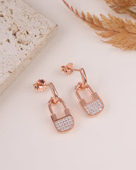 Rose gold lock-shaped earrings with diamond accents on a light surface.