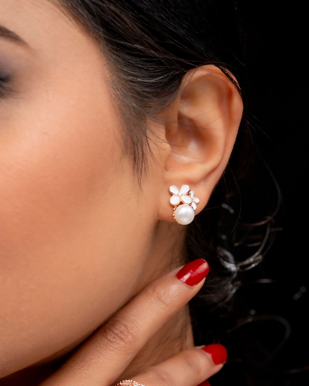 Close-up of an ear wearing pearl earrings with a blurred background