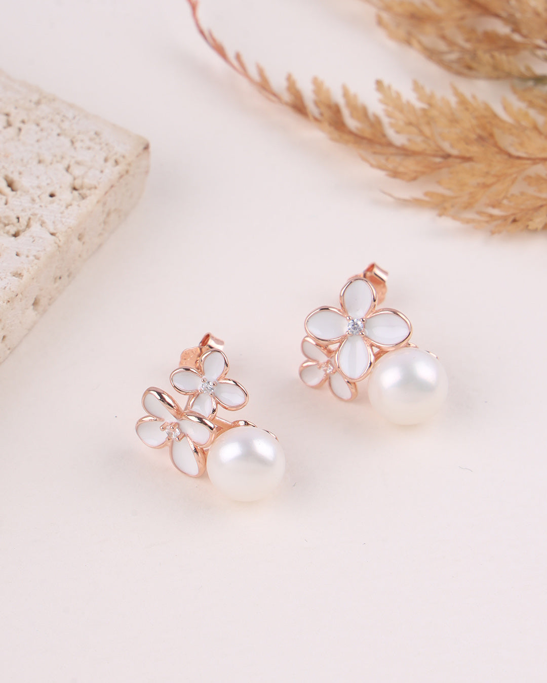 Pair of floral earrings with pearl centers on a light background