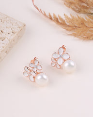 Pair of floral earrings with pearl centers on a light background