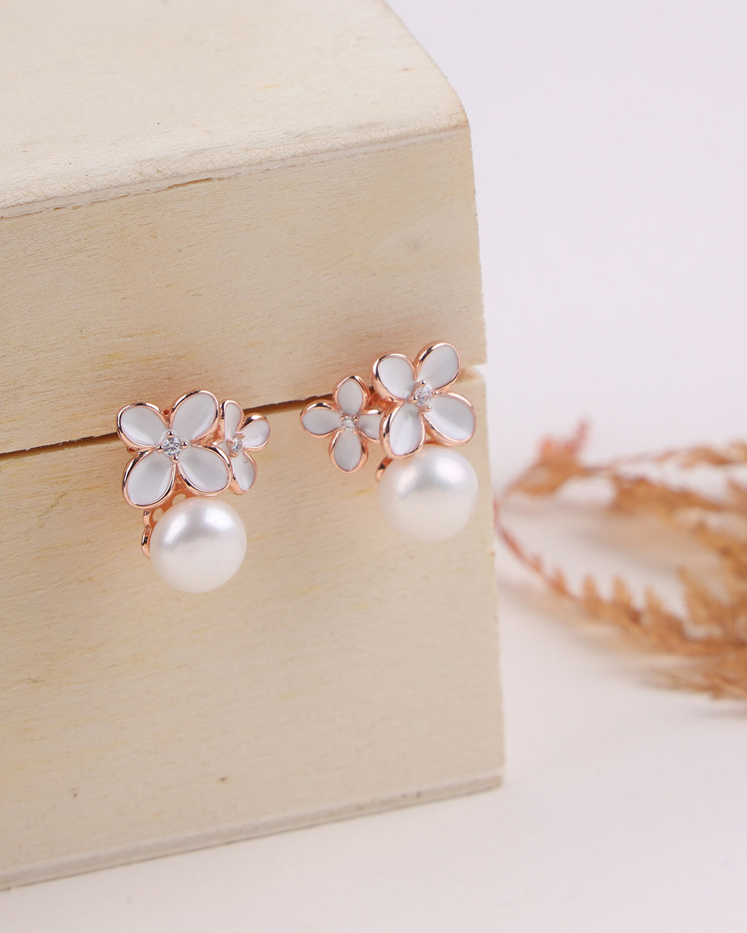 Pair of floral earrings with pearls on a wooden box