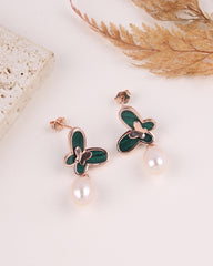 Butterfly-shaped earrings with green accents and pearl drops on a light background