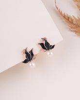 Pair of black leaf-shaped earrings on a light beige background