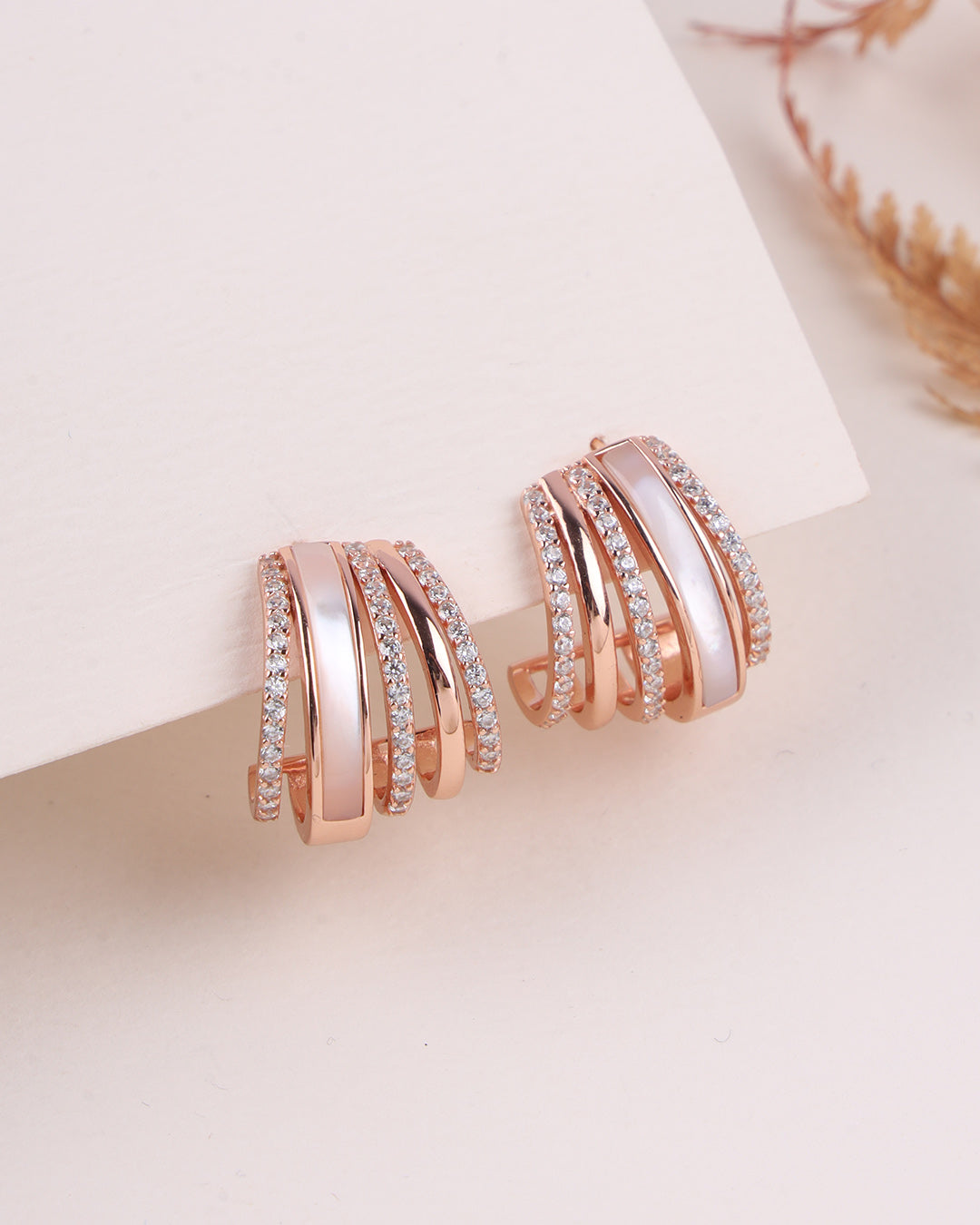 Rose gold hoop earrings with diamond accents on a light background